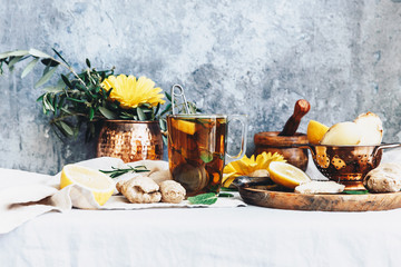 Glass mug of ginger tea with  lemon, ginger  and mint on rustic table