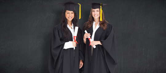 Full length shot of two women graduating against blackboard