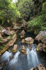 Beautiful landscape of a rocky pond, stream and lush vegetation next to the Tham Chang (or Jang or Jung) Cave in Vang Vieng, Laos.