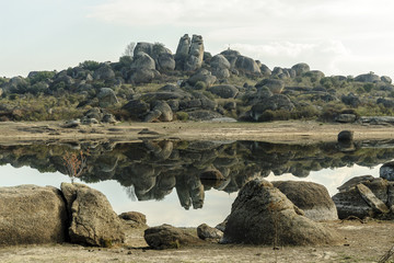 scenery with reflexes in the water of the park and natural monument of the Barruecos in Malpartida...