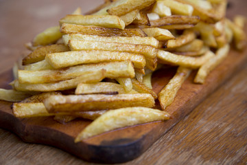 Side view of french fries on wooden board. Closeup.