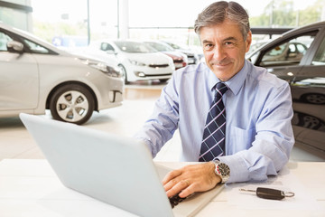 Smiling salesman behind his desk