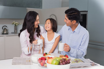 Happy young girl enjoying breakfast with parents