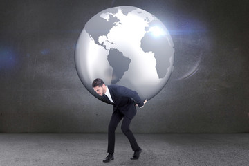 Businessman carrying the world against grey room