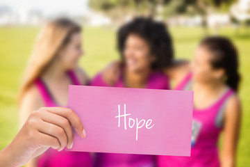 The word hope and hand holding card against three laughing runners supporting breast cancer marathon 