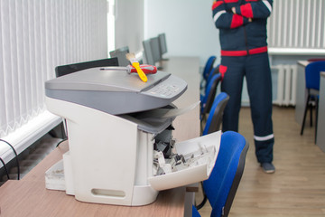 The specialist repairman serves or repairs the laser printer with a screwdriver and a brush....