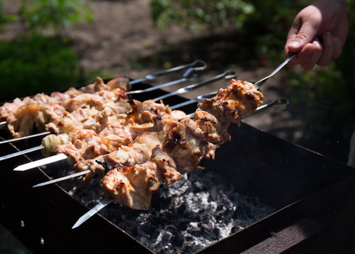 Hand holding meat on a skewer. Cooking shish kebab on the fire.