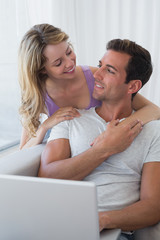 Relaxed couple using laptop on couch