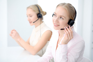 Naklejka premium Image of bright call center. Focus on young beautiful woman in a headset