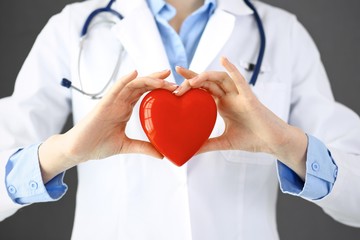 Female doctor with stethoscope holding heart in her arms. Healthcare and cardiology concept  in...