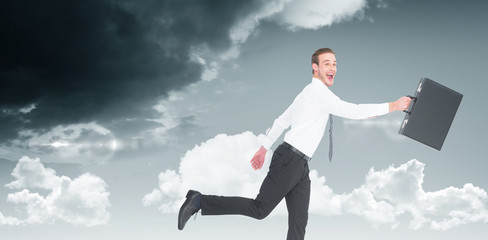 Happy businessman leaping with his briefcase against blue sky