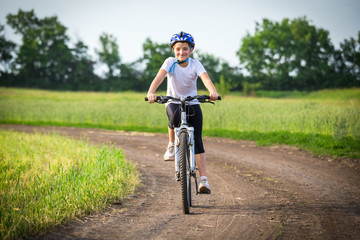Fototapeta premium Smiling girl ride on bike on rural landscape