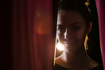 Ballet dancer peeking through a stage curtain