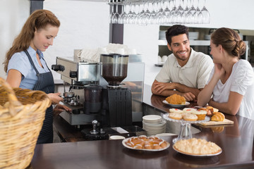 Smiling couple with female cafe owner at coffee shop