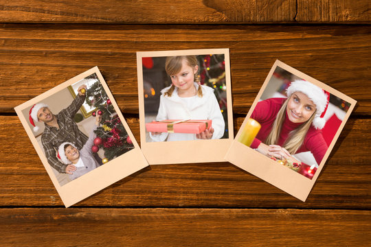 Instant photos on wooden floor against smiling son and dad decorating the christmas tree