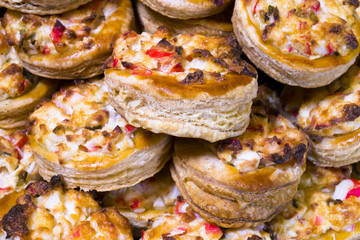 Baked portioned round tartlets made of puff pastry with crab cheese and onion filling