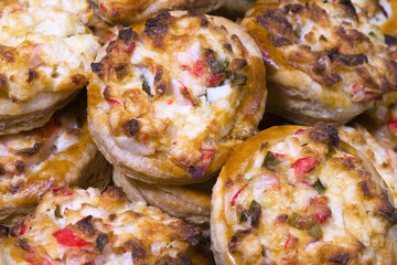 Baked portioned tartlets made from puff pastry with crab cheese and onion filling