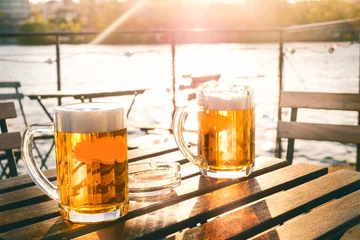 Photo sur Plexiglas Bière Two glasses of light beer with foam on a wooden table.On a boat. Garden party. Natural background. Alcohol. Draft beer. Landscape, golden.