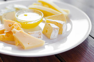 Cheese plate. Assortment of various types of cheese on wooden cutting board.