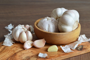 Garlic bulbs in wooden bowl and garlic cloves on wooden board