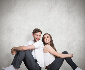 Young couple sitting on floor against weathered surface 
