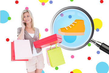 Happy blonde with shopping bags on the phone against dot pattern