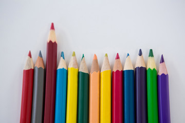 Colored pencils arranged in a row on white background