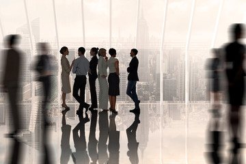 Business colleagues talking against room with large window looking on city