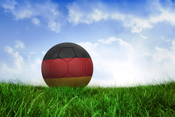 Football in germany colours on field of grass under blue sky