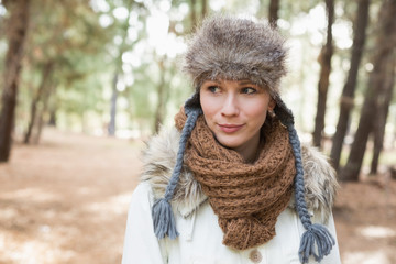 Woman wearing fur hat with woolen scarf and jacket in woods