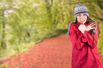 Cold redhead wearing coat and hat against peaceful autumn scene in forest