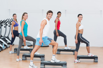 Naklejka na ściany i meble Fitness class performing step aerobics exercise