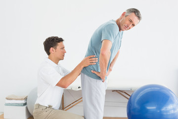 Therapist massaging mans lower back in gym hospital