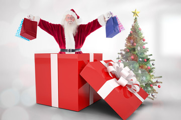 Santa standing in large gift against christmas tree in bright room