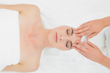 Hands massaging a womans forehead at beauty spa