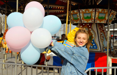 Obraz na płótnie Canvas Beautiful young woman with balloons in the amusement park