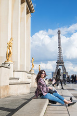 Fototapeta na wymiar Beautiful woman sitting near the Eiffel Tower in Paris, France
