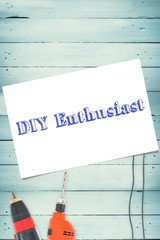 The word diy enthusiast and white card against tools on wooden background