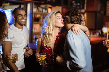 Friends looking at woman embracing man in club