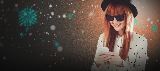 Smiling hipster woman texting with her smartphone against snow with red flakes