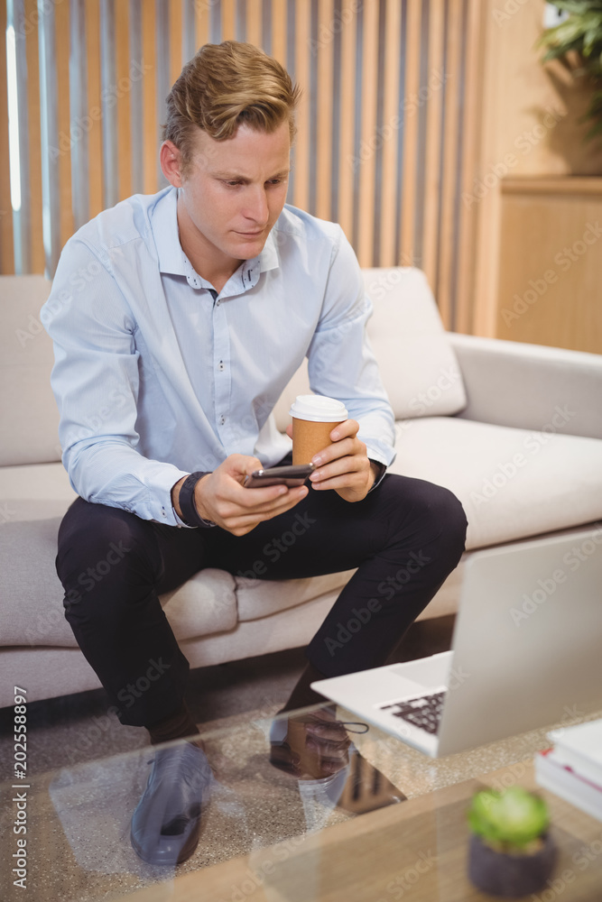Aufkleber attentive executive using mobile phone while having coffee