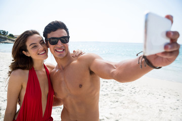 Smiling young couple taking selfie at beach