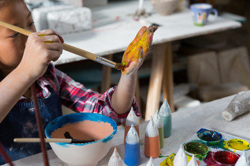 Girl painting her hand with paint brush