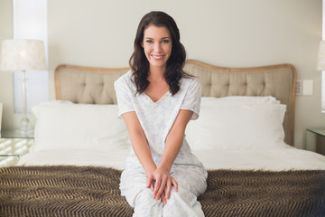 Pleased pretty brown hair woman sitting on a bed