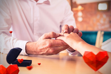 Obraz na płótnie Canvas Hearts against man putting engagement ring on womans finger 3D