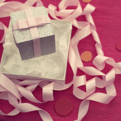 Festive composition with gift box on a bright pink background.