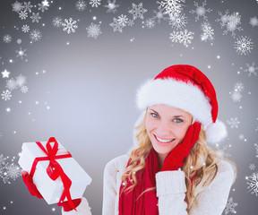 Happy festive blonde with gift against grey vignette