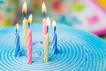 Close up of candles lit on top of frosted cake