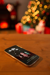 Santa elf and reindeer against smartphone on table at christmas 