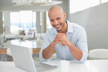 Smiling casual man using laptop at home